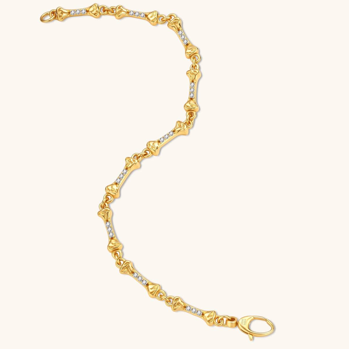 Gold-plated sterling silver bracelet with bone-shaped links, embedded CZ stones, and lobster clasp on light background.