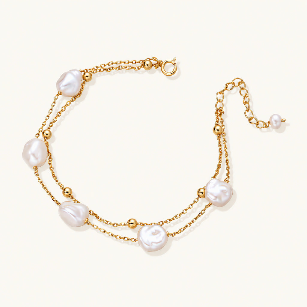 Double-strand gold bracelet with irregular baroque pearls and smooth freshwater pearls on cream background.