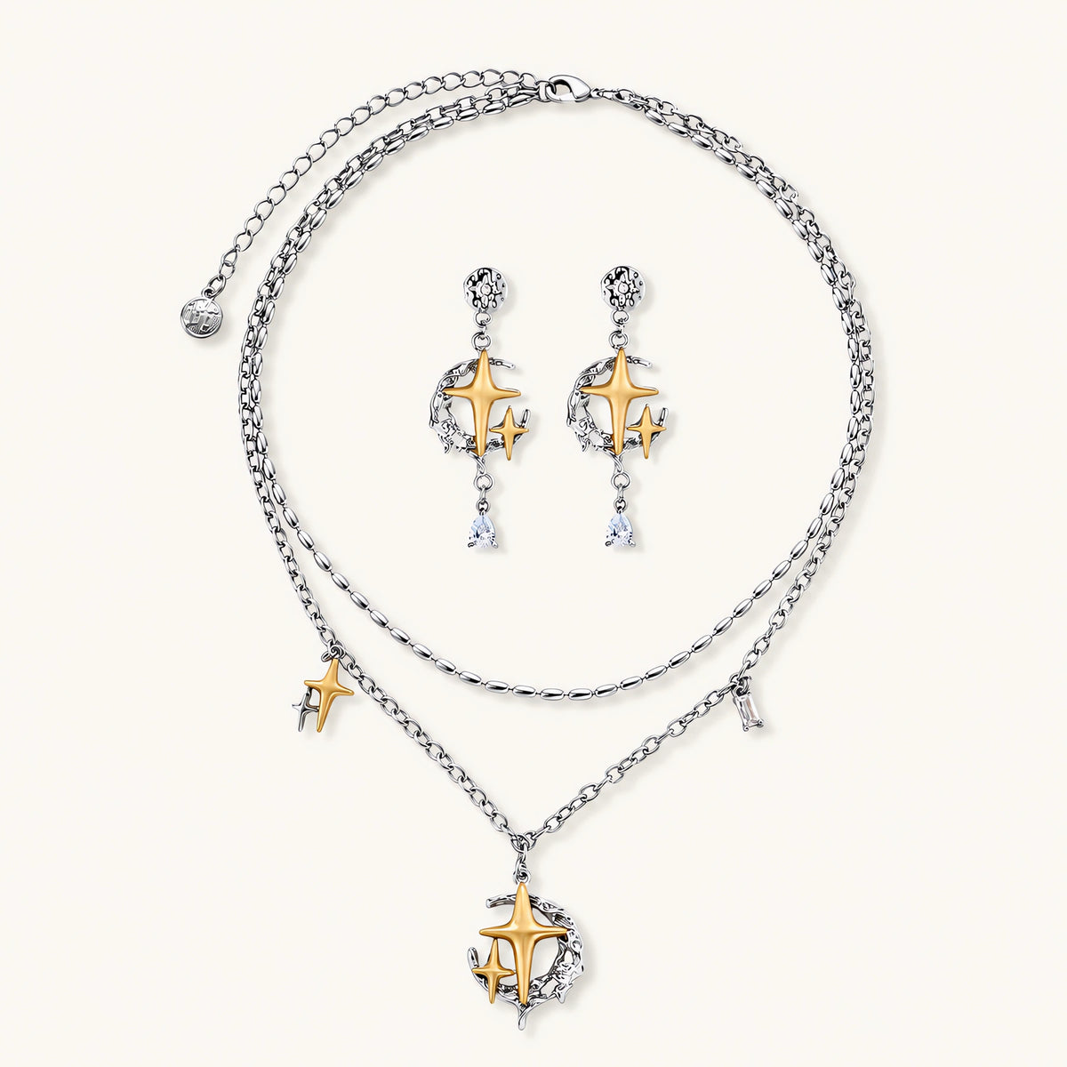 Delicate eco-brass jewelry set featuring gold star and silver moon crescents with clear zirconia crystal drops on cream background