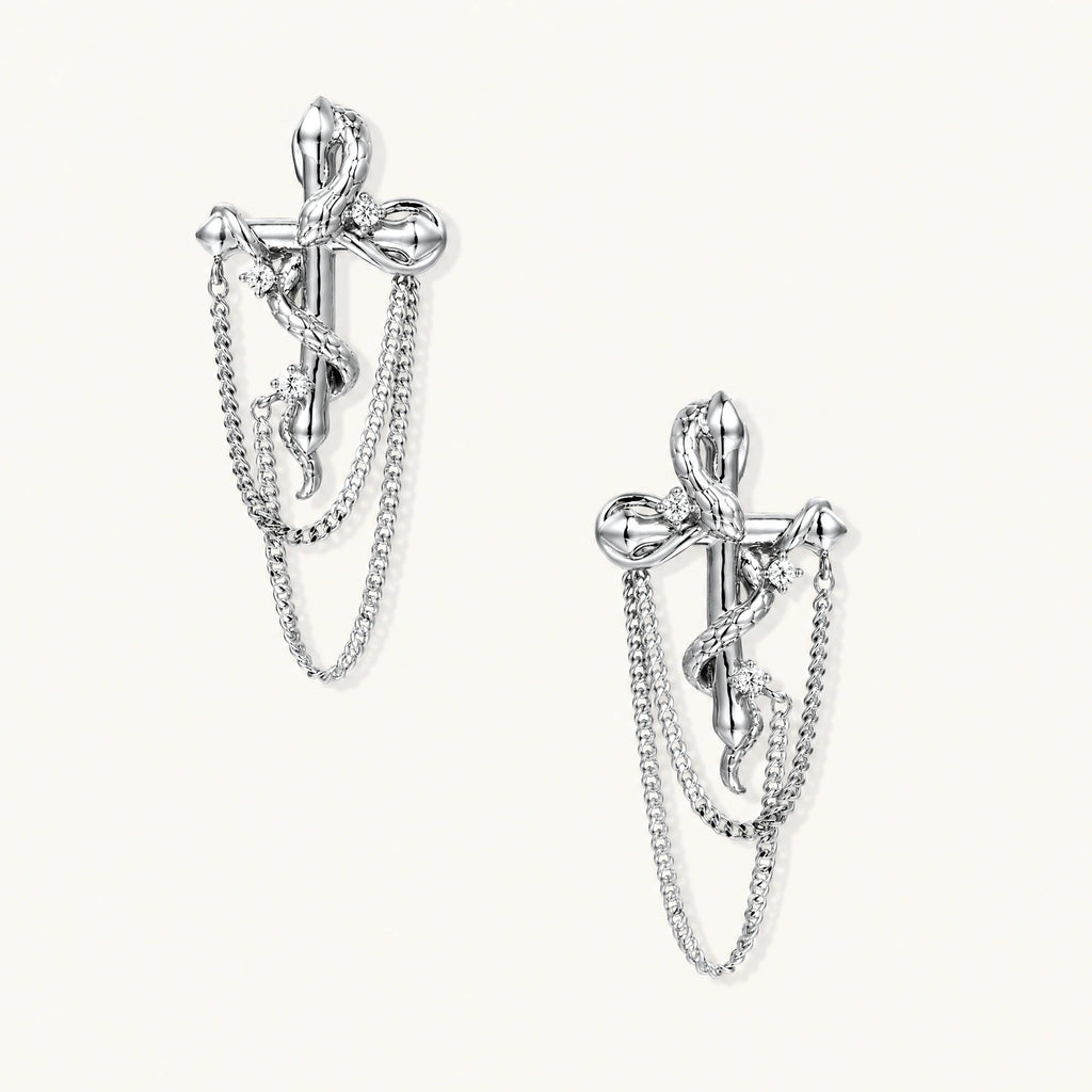 Sculptural white gold bow earrings with cascading chain details on neutral background