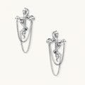 Sculptural white gold bow earrings with cascading chain details on neutral background