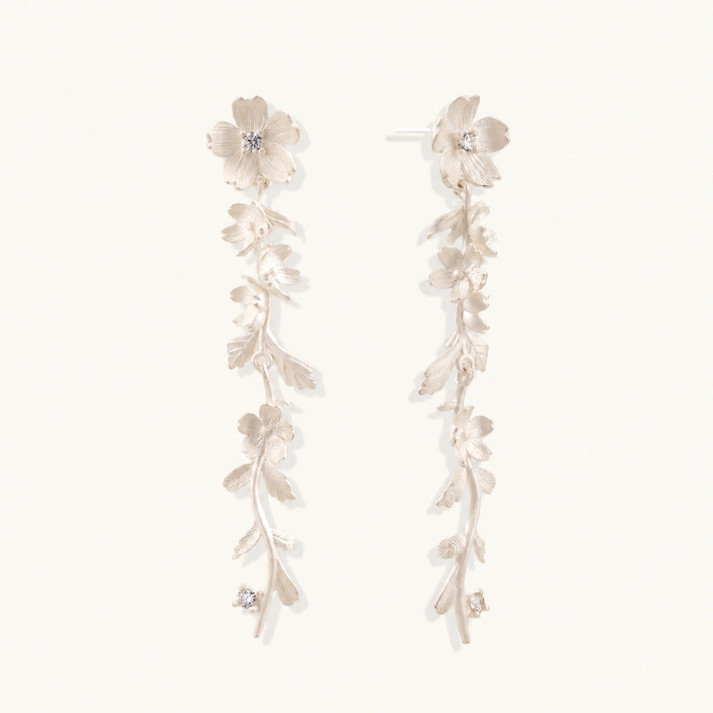 Long sterling silver drop earrings with delicate floral vine design and crystal accents on white background