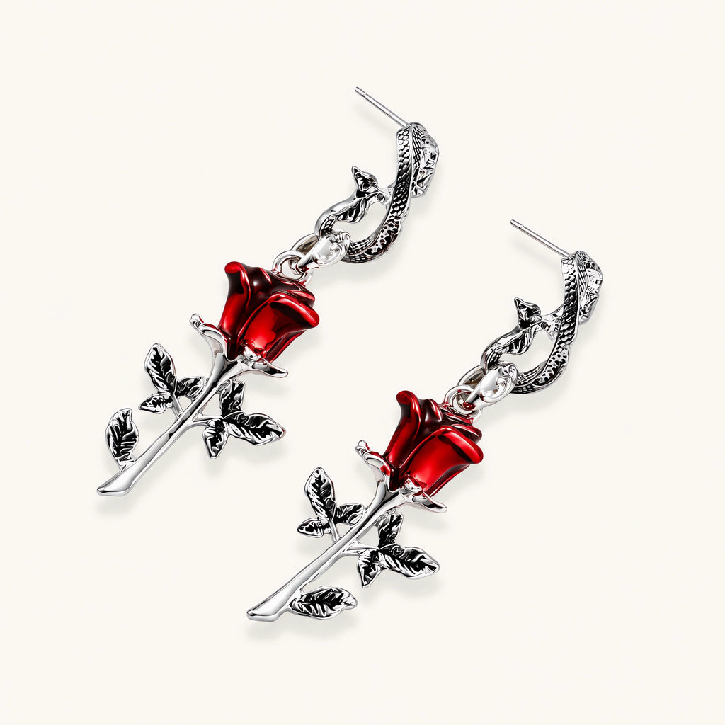 Gothic jewelry set with silver snake designs holding red enamel roses, featuring detailed leaf stems on cream background