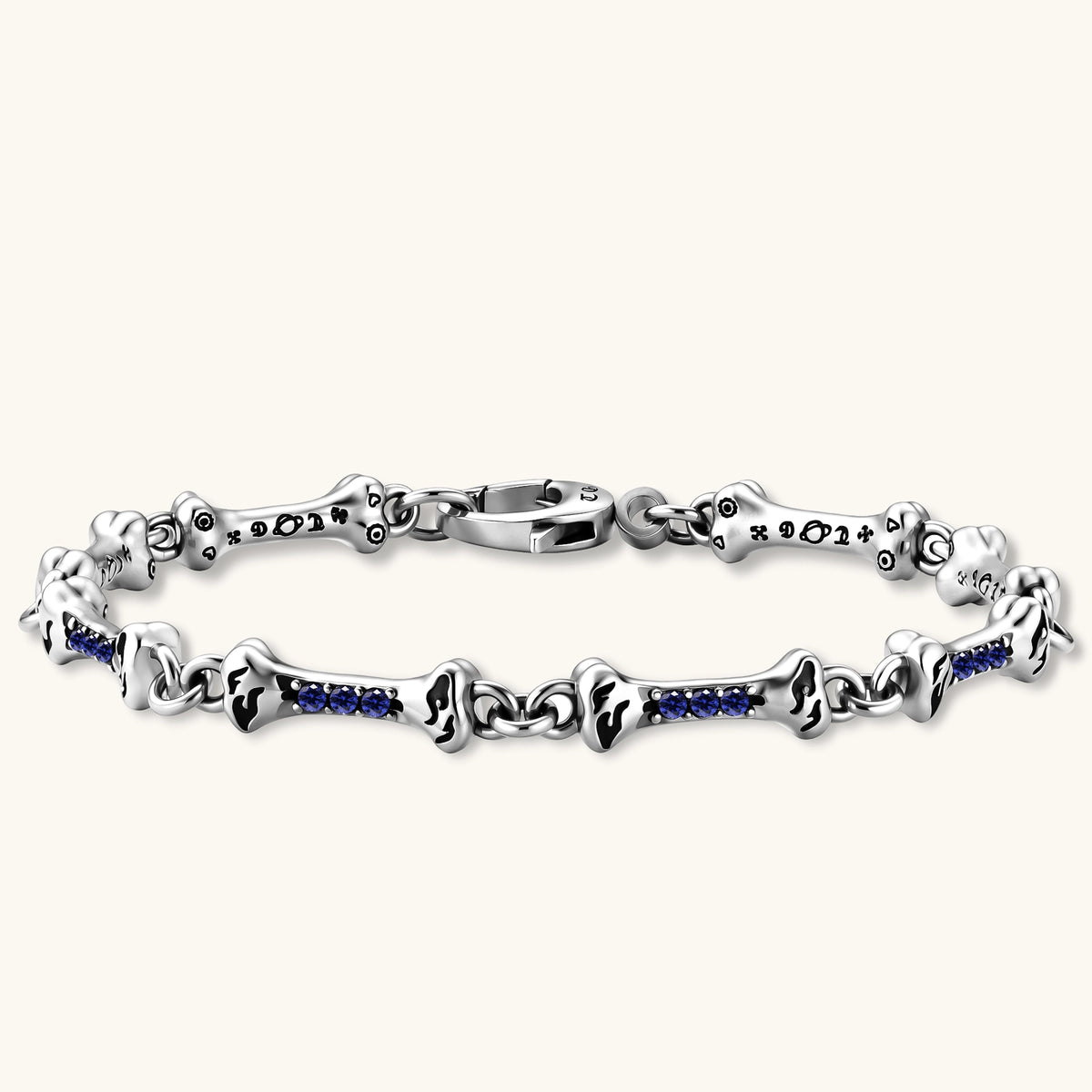 Sterling silver bone-link bracelet with blue cubic zirconia stones and engraved motifs, lobster clasp, on cream background.